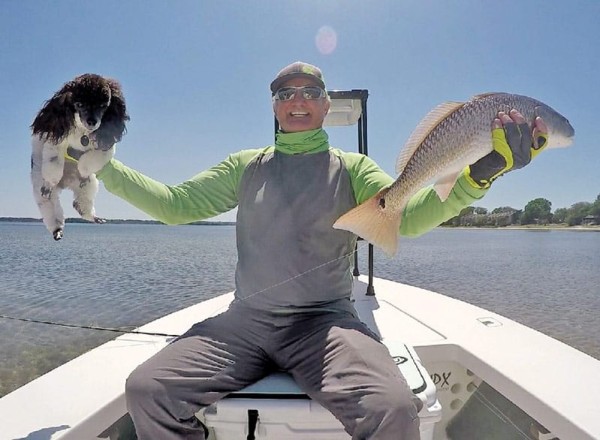 Capt. Steve Bachman haulin' reds with his fishing buddy Moxie.