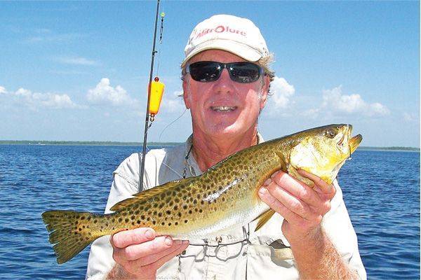 Captain Pat With a very "yellowed" Speckled trout caught 8/11 on a live pinfish under a Back Bay Thunder.