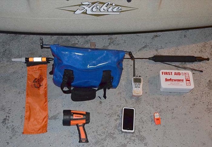 Safety essentials, from left to right: 360-degree light, dry bag, spotlight, handheld VHF radio, mobile phone, first aid kit, and a whistle. Photo credit: Brandon Barton.