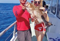 Capt Rod helps guest show off her big red grouper caught aboard the Catch My Drift.