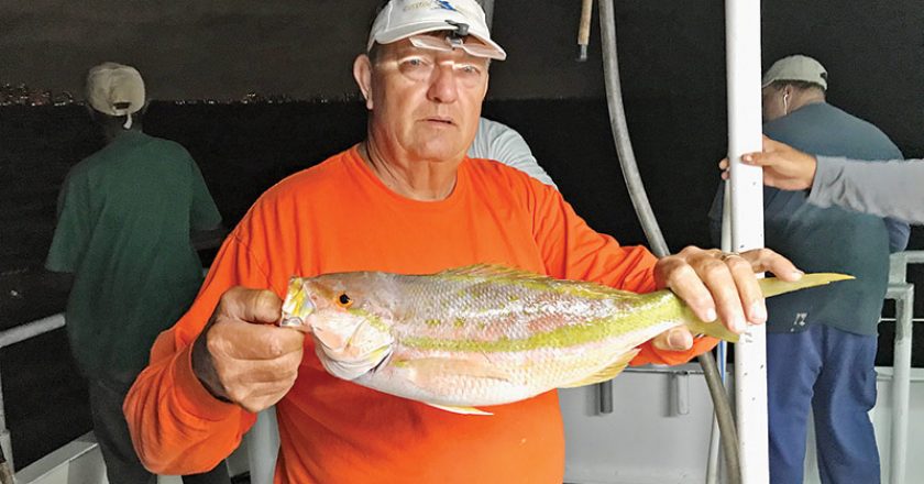 Gene with a nice yellowtail snapper caught night anchor fishing aboard the Catch My Drift.