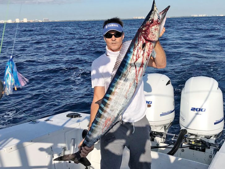 Eddie Walters with a Christmas wahoo caught on a horse ballyhoo rigged behind a black and orange Islander.