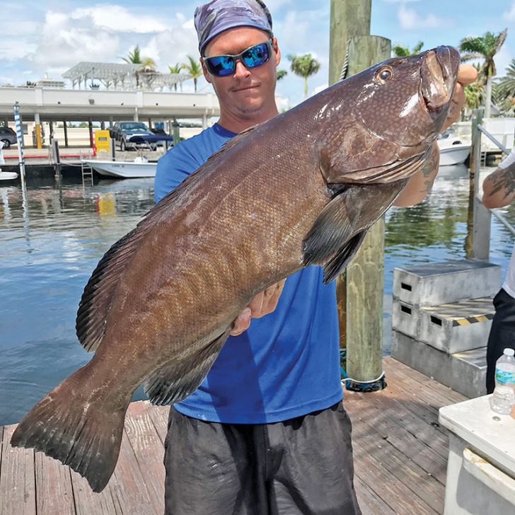 Tyler with a monster black grouper caught aboard the Catch My Drift.
