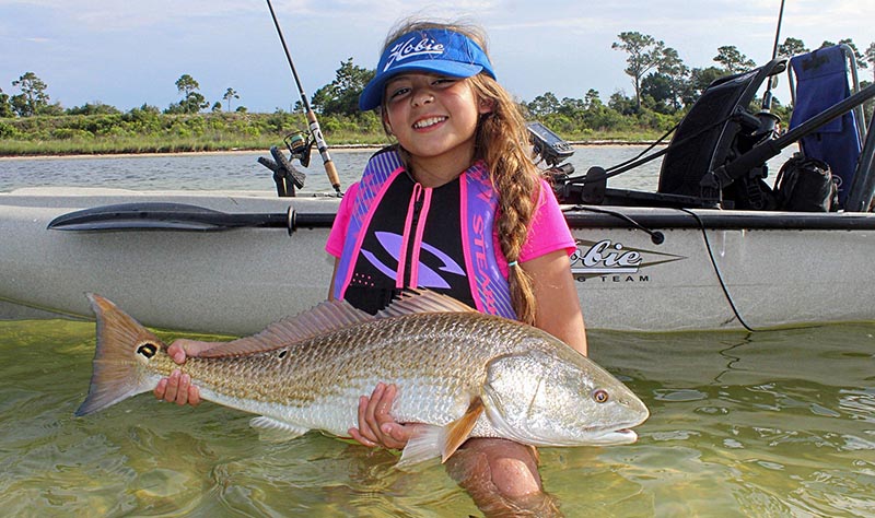 My 11-year old daughter with the first big redfish she ever caught. PHOTO CREDIT: Brandon Barton.