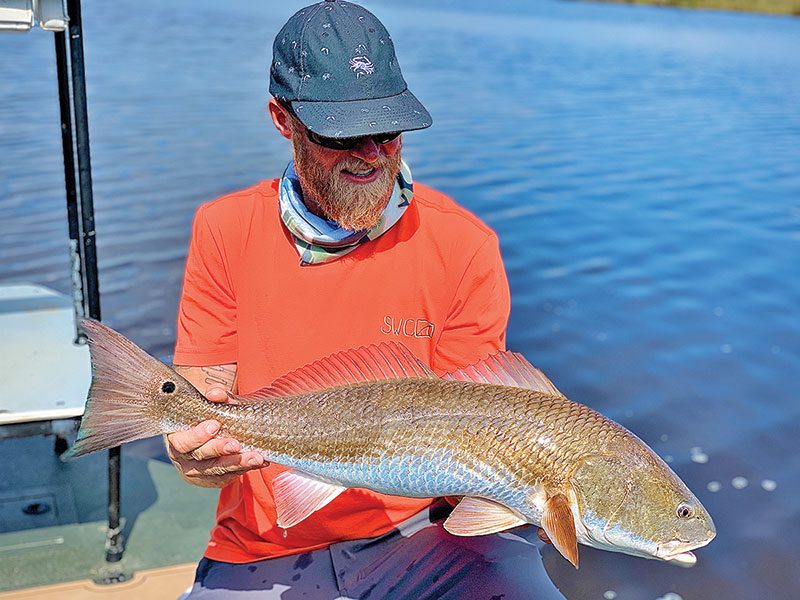 Scott Burgess from Tallahassee with a beautiful upper slot redfish caught on a Slayer INC stick bait in pearl white color.