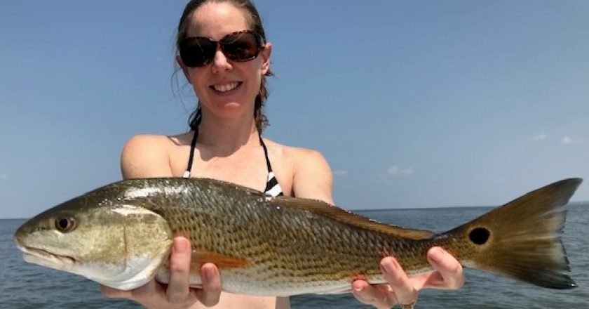 Julia Mahatekar proudly displays her redfish taken on the Eastern Shore of Mobile Bay.