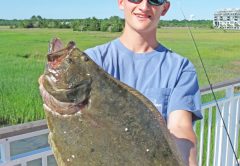 boy holding flounder during june fishing