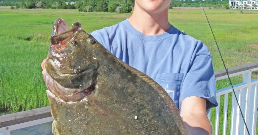 boy holding flounder during june fishing