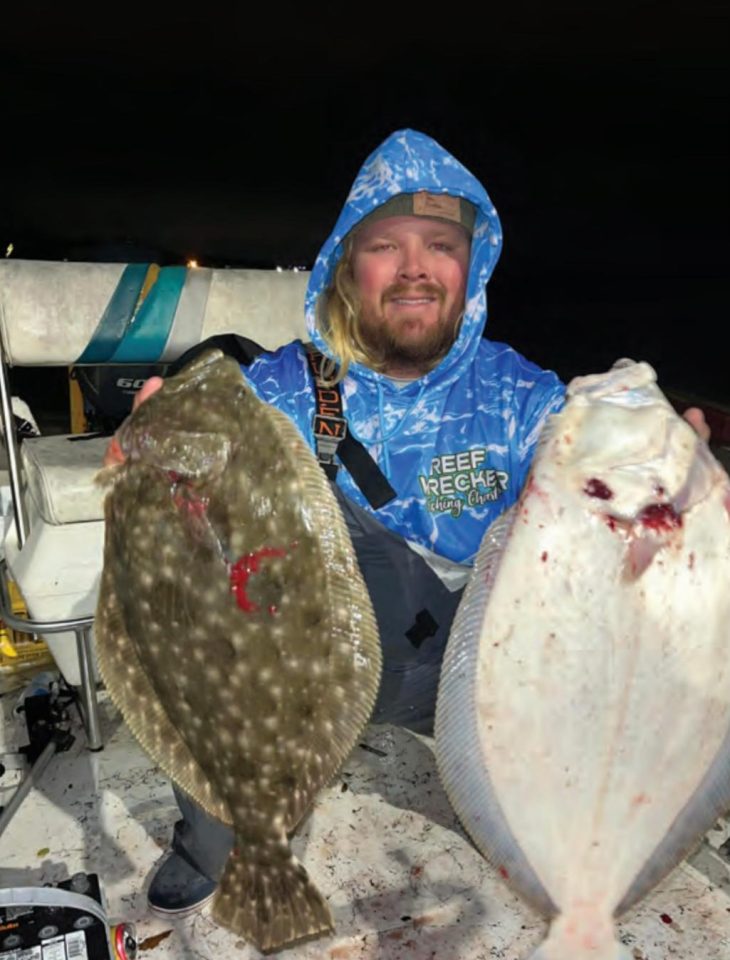 Capt. John Ellis in a blue Reef Wrecker hoodie holding up two big flounder on his boat at night, one dark side up and one white side up