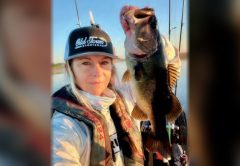 Wendy Biles in an Old Town Sportsman cap and life vest holding up a largemouth bass by the lip
