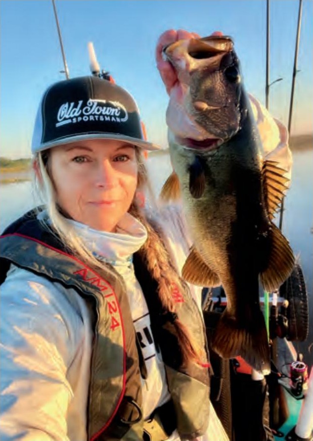 Wendy Biles in an Old Town Sportsman cap and life vest holding up a largemouth bass by the lip