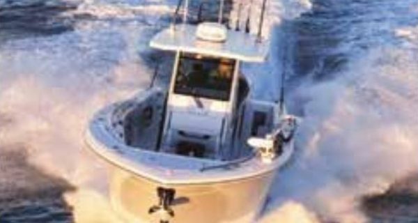 A center console fishing boat with outriggers running fast across the open ocean, leaving a wide white wake