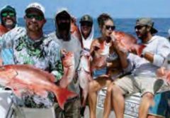 Seven anglers on a boat holding up red snapper caught offshore