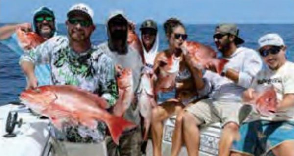 Seven anglers on a boat holding up red snapper caught offshore
