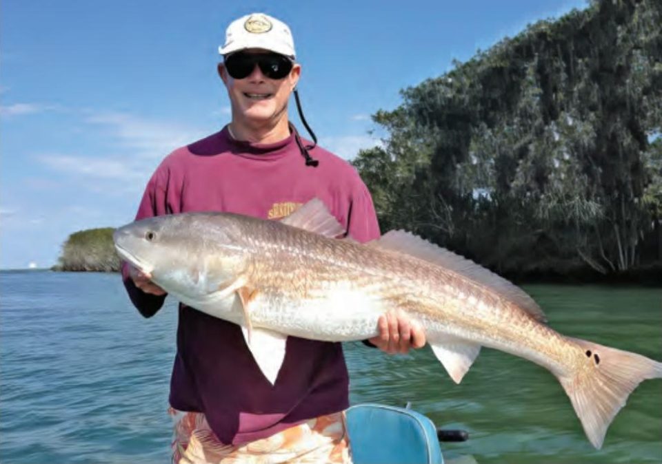 Keith holding the monster redfish he caught with an 8-inch chunk of bluefish along a drop off in Florida's Indian River Lagoon