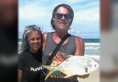 Marco Pompano holding a pompano on the beach next to a smiling woman