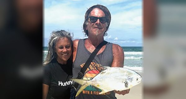 Marco Pompano holding a pompano on the beach next to a smiling woman