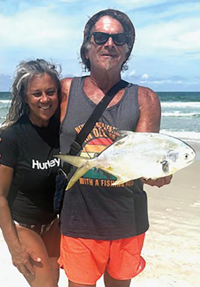 Marco Pompano holding a pompano on the beach next to a smiling woman