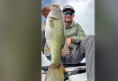 Pro bass angler Joey Bloom holding up a big largemouth bass on a boat