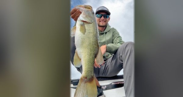 Pro bass angler Joey Bloom holding up a big largemouth bass on a boat