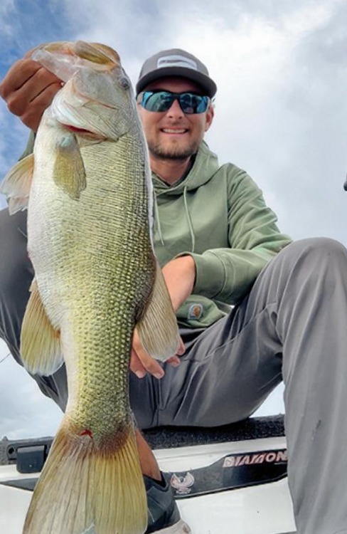 Pro bass angler Joey Bloom holding up a big largemouth bass on a boat