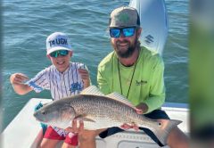 Capt. Jeff Patterson of Pole Dancer Fishin' Charters and a young angler holding a redfish on his boat