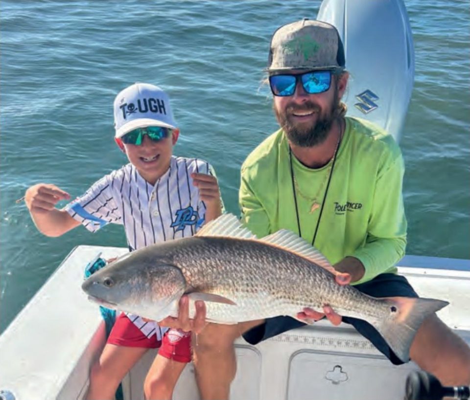 Capt. Jeff Patterson of Pole Dancer Fishin' Charters and a young angler holding a redfish on his boat