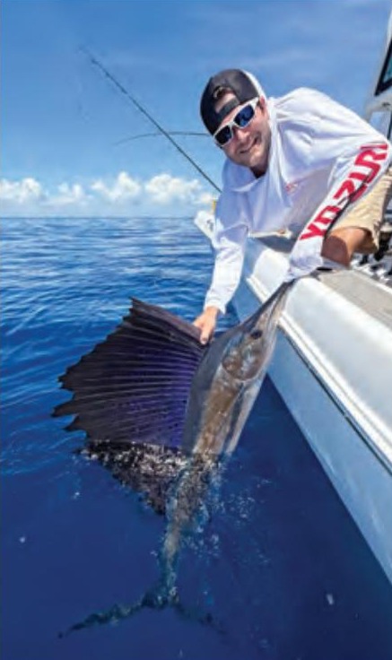 An angler leaning over the side of a boat to release a sailfish