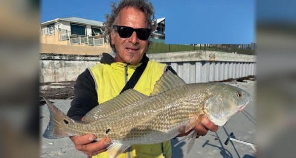Marco Pompano on the beach holding the redfish he caught by hand line