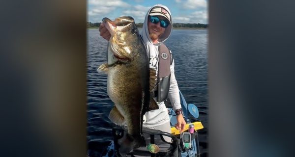Devin Holbrook holding a big largemouth bass on his kayak