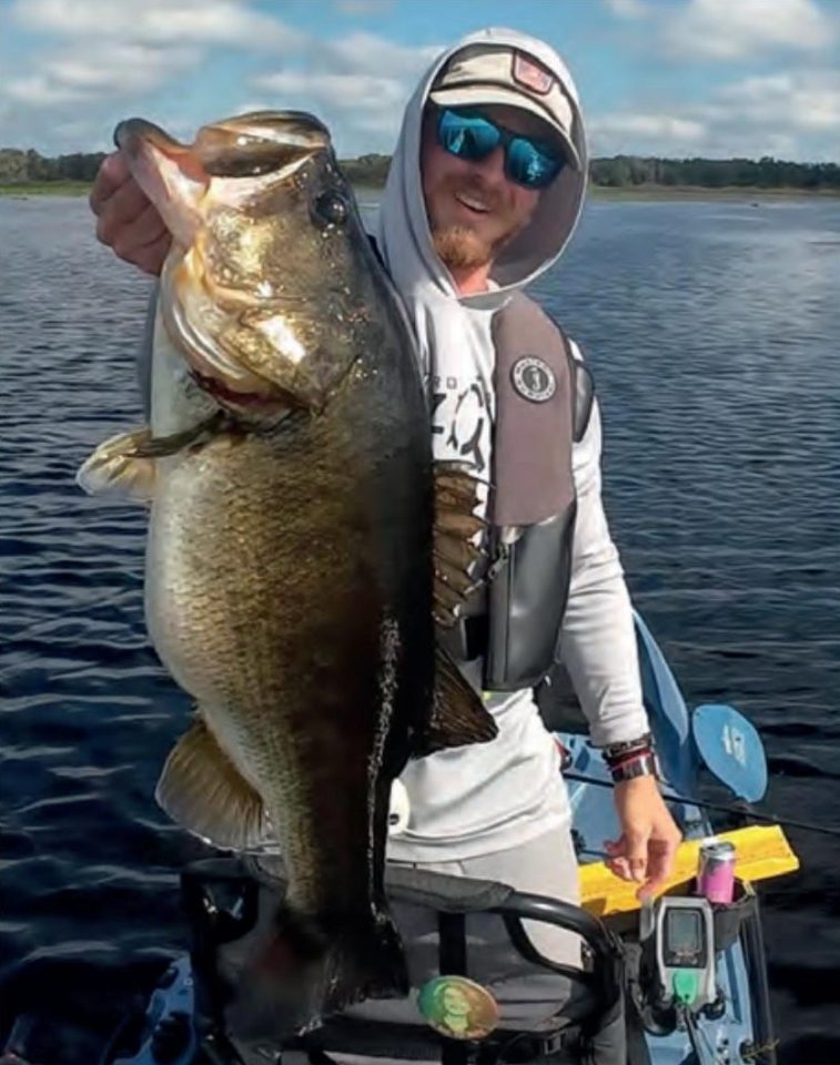 Devin Holbrook holding a big largemouth bass on his kayak