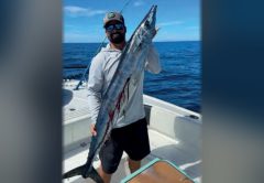 Capt. Evan Sanders of Sol Fishing holding a wahoo on a boat