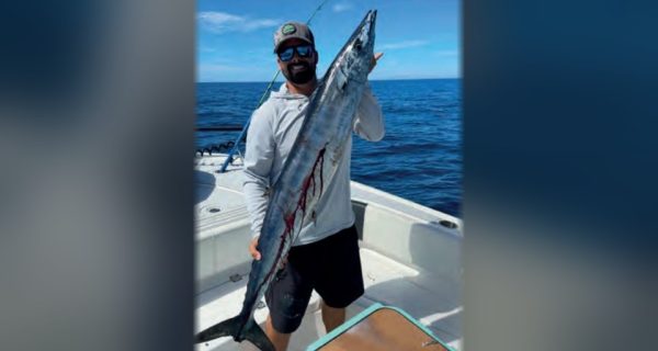 Capt. Evan Sanders of Sol Fishing holding a wahoo on a boat