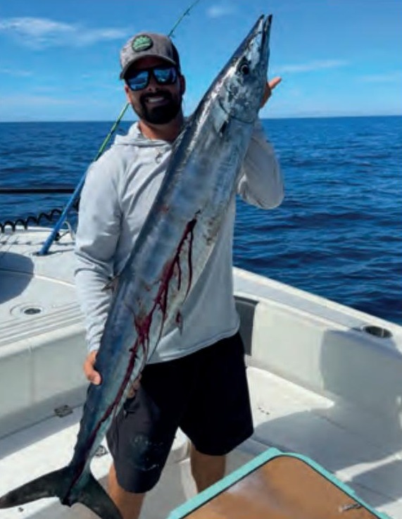 Capt. Evan Sanders of Sol Fishing holding a wahoo on a boat