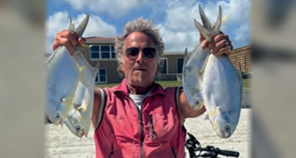 Marco Pompano holding up a pompano in each hand on the beach