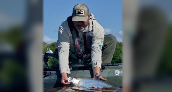 An angler releasing a tarpon beside his kayak