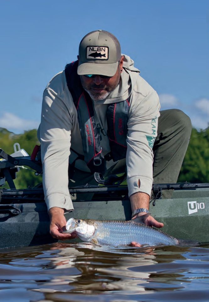 An angler releasing a tarpon beside his kayak