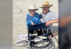 Two anglers on the beach with a catch of pompano, black drum, sheepshead, and whiting