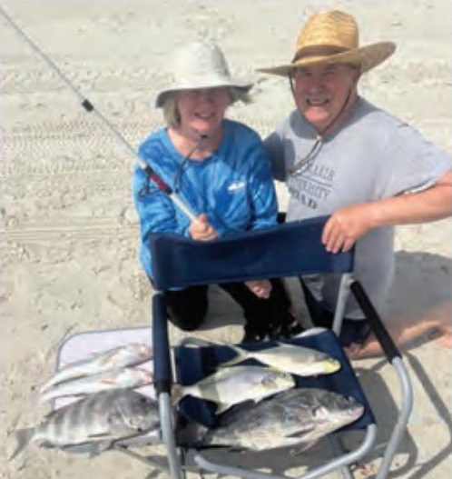 Two anglers on the beach with a catch of pompano, black drum, sheepshead, and whiting