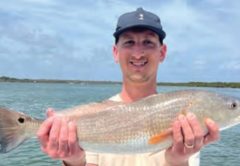 Smiling angler holding a redfish on a boat