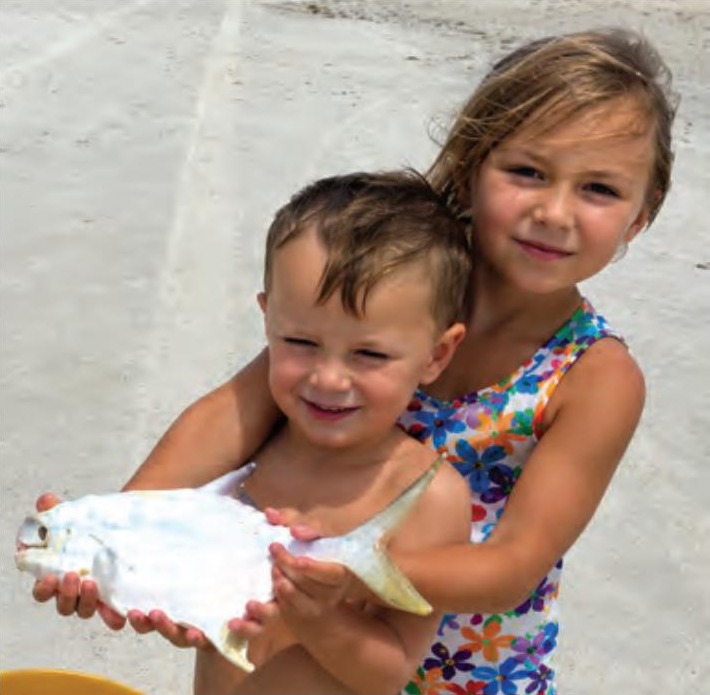 Two young children holding a pompano on the beach
