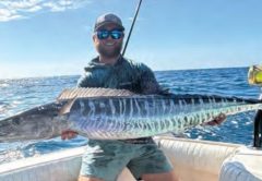 Capt. Kevin Moran of Strippin Lips Fishing Charters holding a wahoo on a boat