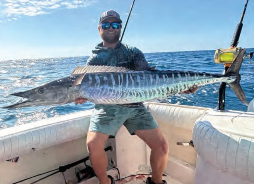 Capt. Kevin Moran of Strippin Lips Fishing Charters holding a wahoo on a boat