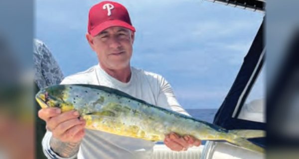 An angler in a red cap holding a mahi on a boat