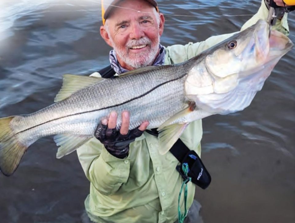 An angler standing in the water holding a big snook