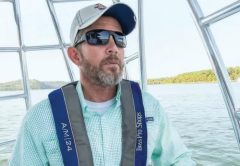 A boater at the helm wearing an inflatable life jacket