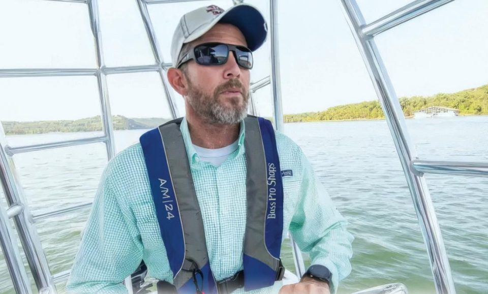 A boater at the helm wearing an inflatable life jacket