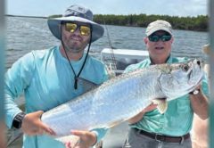 Two anglers holding a tarpon