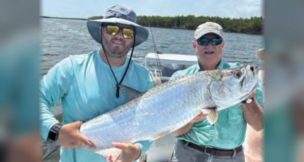 Two anglers holding a tarpon