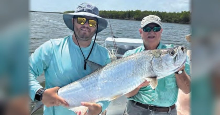 Two anglers holding a tarpon